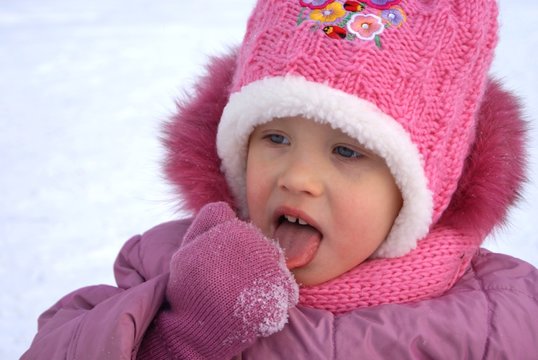 Девочка лижет снег с рукавицы