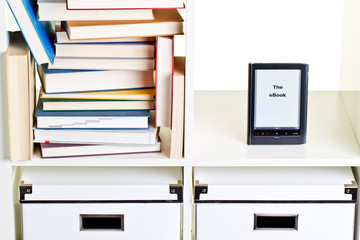 e-book reader im regal neben bücherhaufen
