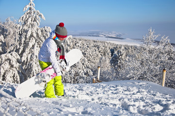Beautiful woman with snowboard stands on top mountain