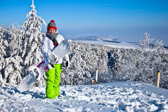 Beautiful woman with snowboard stands on mountain.
