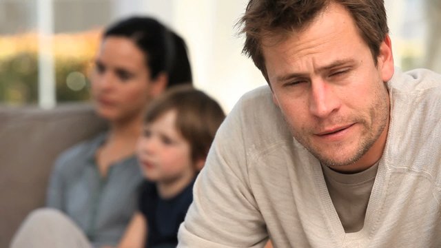 A man is worring while his family is on the sofa