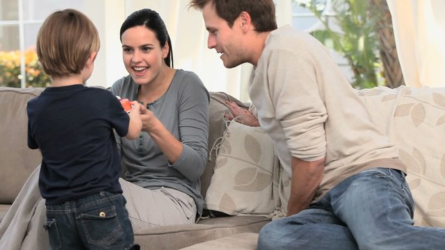 Cute boy bringing cake to their parents in the living room