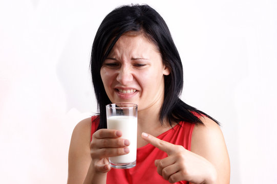 junge Frau zeigt auf ein Milchglas