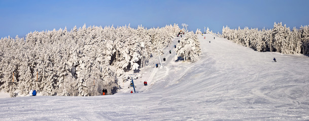 Ski slope with a lift in a snowy forest. Winter landscape.