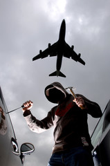 Car thief breaking in to car parked at airport, plane overhead