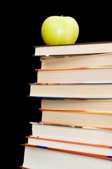 Stack of books and apple On a black background