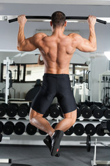 young bodybuilder training in the gym: back - Wide-Grip Front Pull-Up