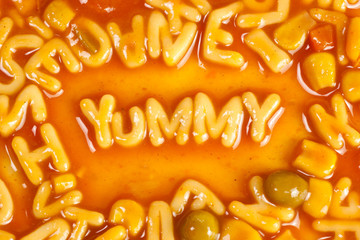 Alphabet shaped pasta forming the word YUMMY in tomato sauce