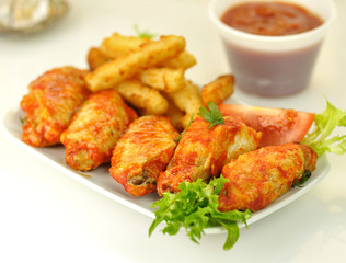 hot chicken wings with salad and fried potatoes