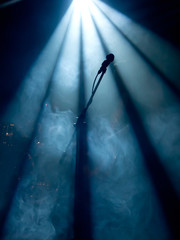 Microphone on stage with stage-lights in the background - obrazy, fototapety, plakaty