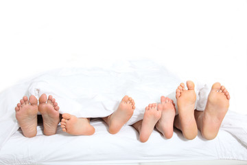 Closeup of family feet in bed - obrazy, fototapety, plakaty