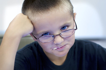 Young boy looking over glasses with birthday cake on his lips