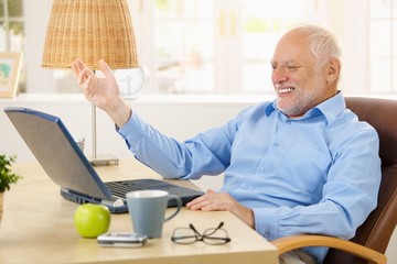 Laughing old man using laptop