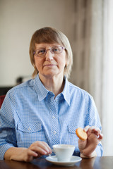 Senior woman having coffee with cookie