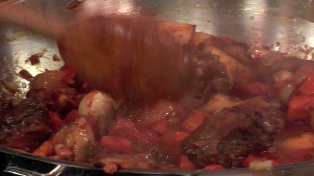 roasting goose in a pan with tomato paste and root vegetables
