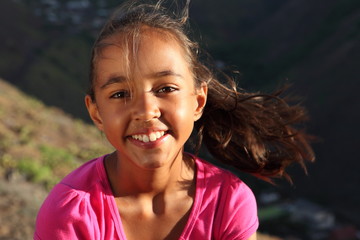 Cute smile from young mixed race girl outdoors on windy day