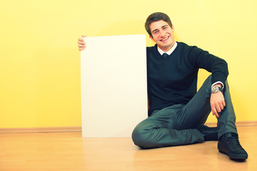 Portrait of a handsome smiling young man sitting and holding a b