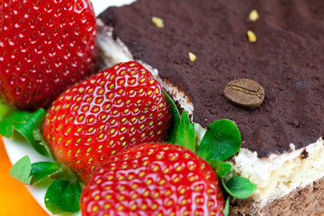 cake on a plate and strawberries lying on the orange fabric