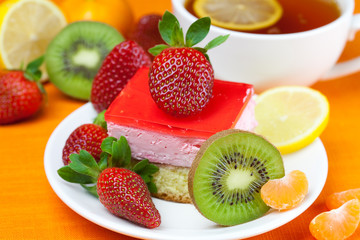 lemon tea, kiwi,cake and strawberries lying on the orange fabric