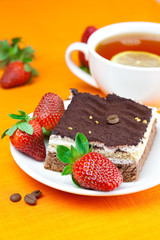 lemon tea, cake and strawberries lying on the orange fabric