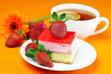 gerbera, lemon tea, cake and strawberries lying on the orange fa