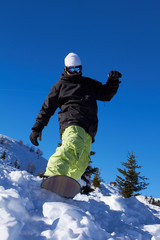 Sporty snowboarder riding on snow in high mountains