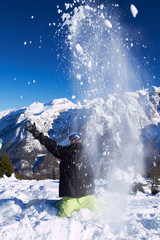 Adult guy throwing snow in the air in high mountains