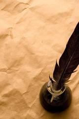 Feather and ink bottle isolated on paper background