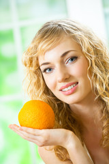 Portrait of young woman with orange at home