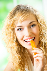 Portrait of young woman eating carrots at home