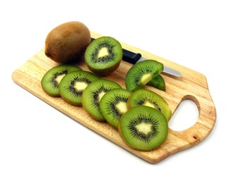 Sliced & whole kiwi fruits on a wooden chopping board
