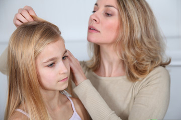 Obraz na płótnie Canvas Mother treating daughter's hair against lice