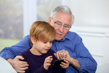 Old man with little boy playing video game on telephone