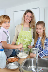 Mother and children in kitchen preparing cake