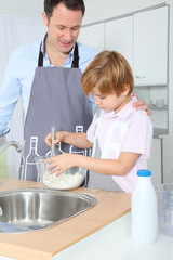 Father and son preparing cake in kitchen