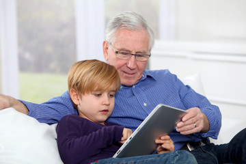 Grandpa with little boy using electronic tablet
