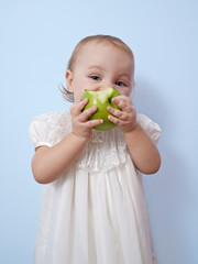 Little girl is eating an apple