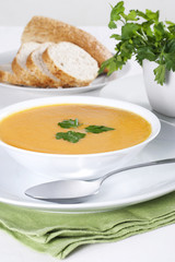 A bowl of soup with parsley and few slices of bread