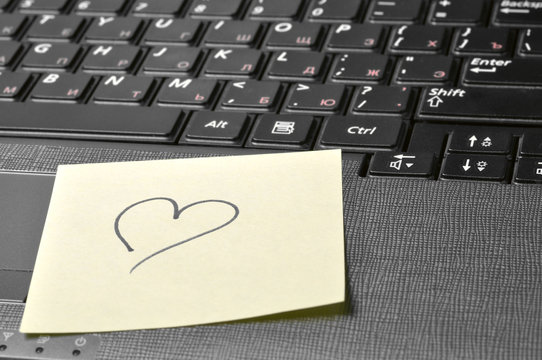computer keyboard with heart on sticky note