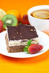 lemon tea, kiwi,cake and strawberries lying on the orange fabric