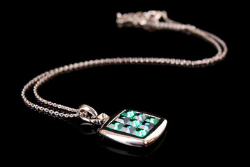 Square pendant with green gem isolated on black