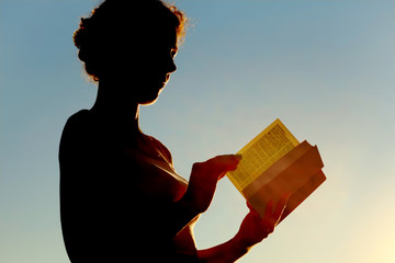 young curl woman reading bible and turning page, side view