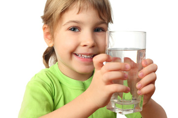 portrait of little girl in green shirt holding glass with water