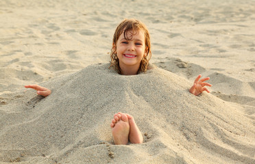 girl after swimming is buried in sand on beach