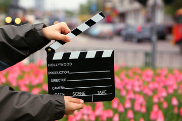 Cinema clapper board in hands of boy on field with tulips