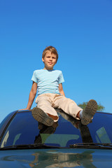 boy sitting on roof of car, blue sky