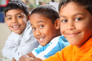 Row of three smiling young school boys in class