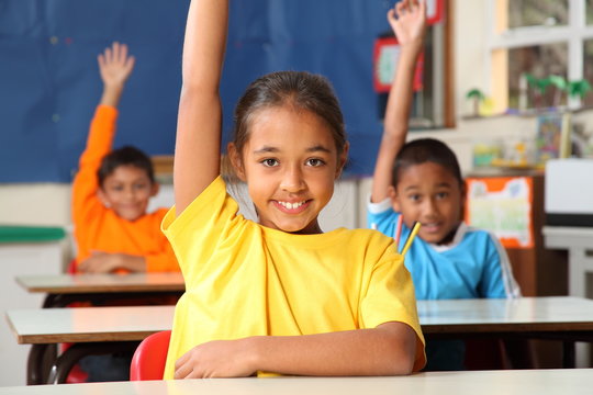 Primary school children signal with raised hands