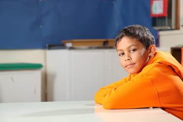 Schoolboy 10 arms folded deep in thought classroom