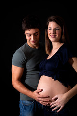 Mom and dad holding pregnant belly isolated on black